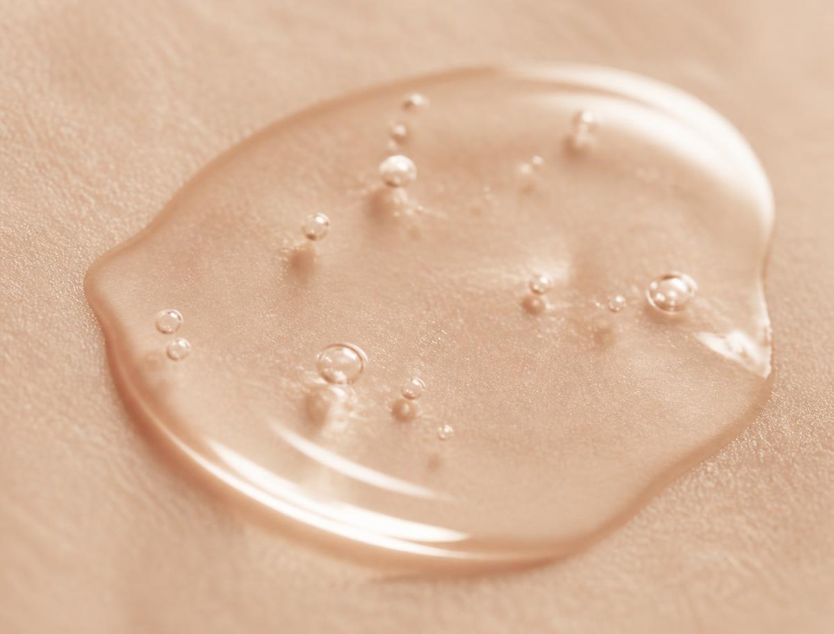 Gota de sérum transparente extendiéndose sobre la piel